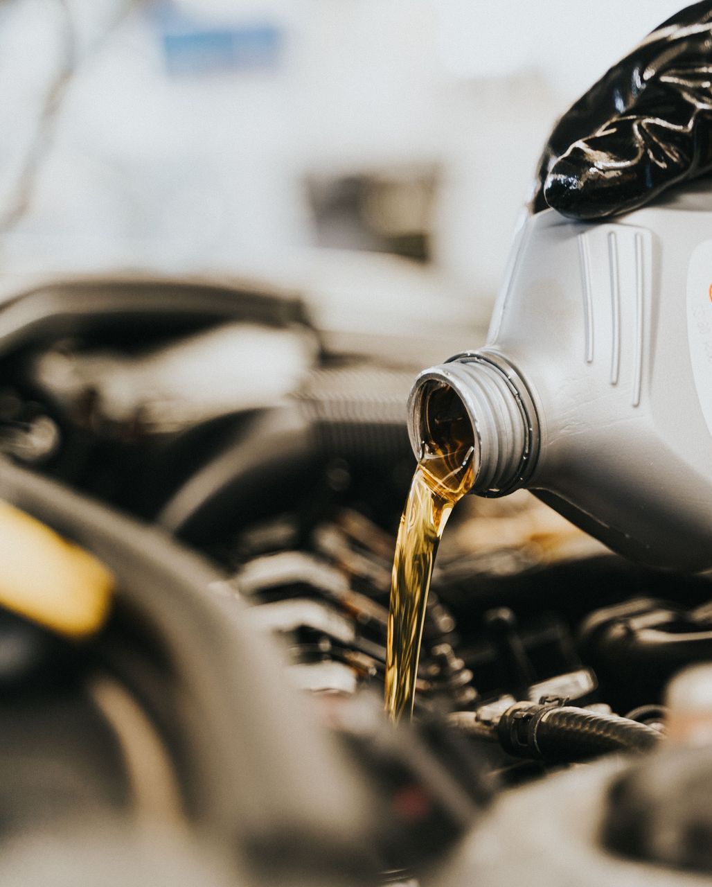 Close-up of a mechanic pouring engine oil into a car engine, highlighting maintenance work.